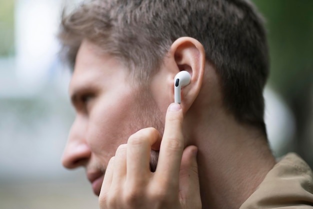 A close up male person using wireless earphones and listen to the music