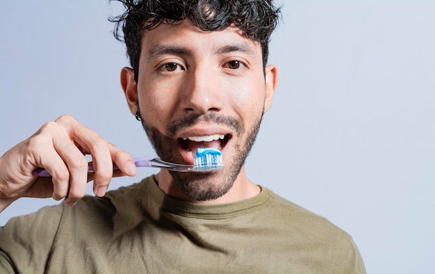 Close up of man brushing his teeth isolated Face of handsome man brushing his teeth Tooth brushing and care concept Face of guy brushing teeth isolated Oral and dental smile concept