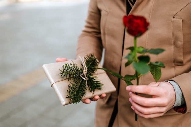 Close up of man giving a rose and a present. Valentine's day.