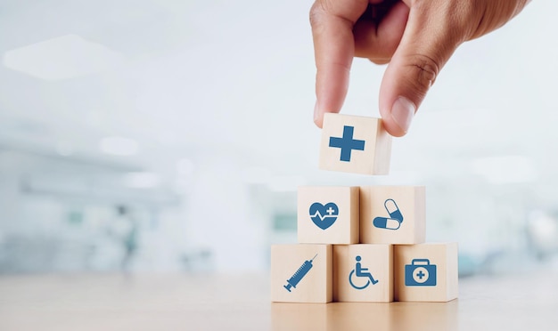 Close up man hand arranging wood block with healthcare medical icon on hospital background