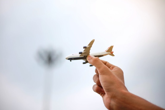 Close up of man hand holding airplane toy model on Sky.Transportation and travel concept.