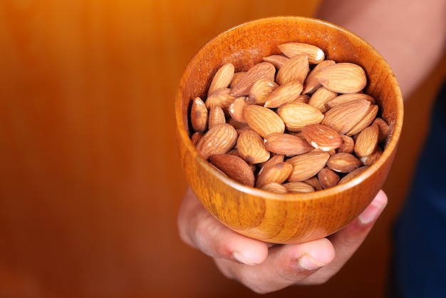 Close up man hand holding a bowl full of almond .