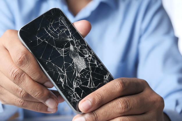 Close up of man hand holding broken smart phone.