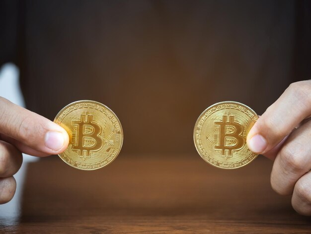 Close up man hand showing gold bitcoin on the table