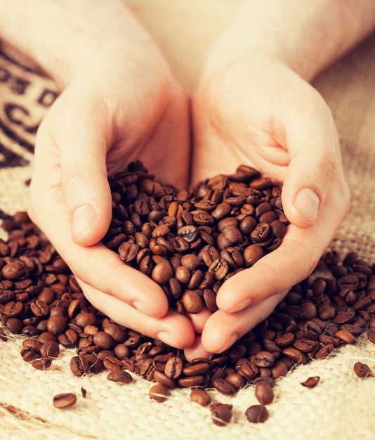 close up of man holding coffee beans