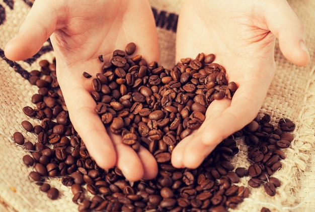 close up of man holding coffee beans