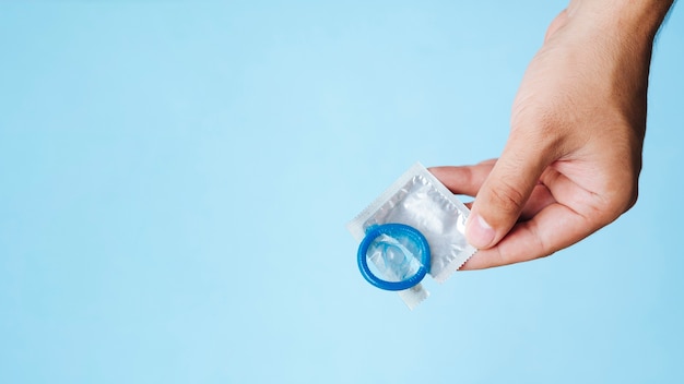 Close-up man holding condom with copy-space