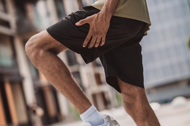 Close up of a man holding his leg in its upper part