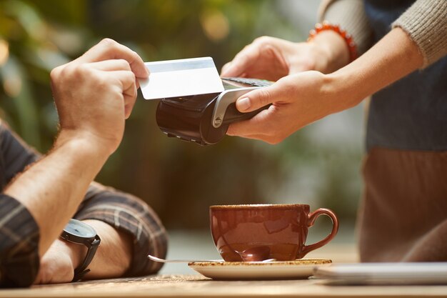 Close-up of man paying with credit card for his order to the waiter in cafe