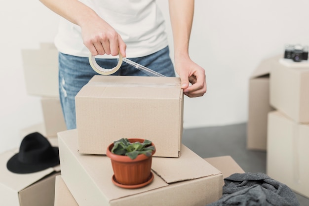 Photo close-up man putting cello tape on box