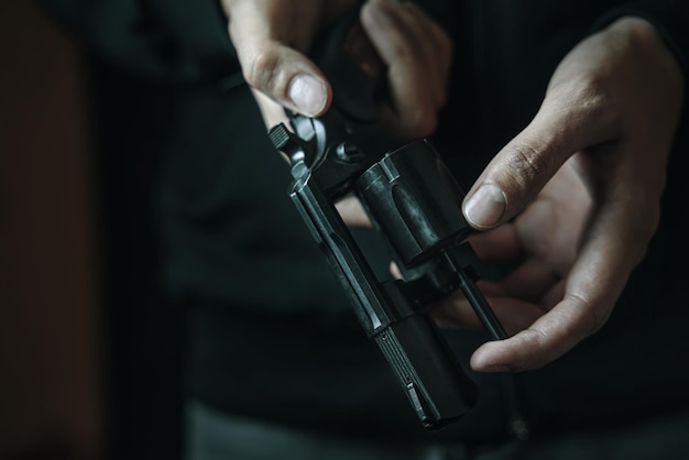 Close up of man reloading revolver persons hands check for bullets in gun barrel guy prepares pistol...