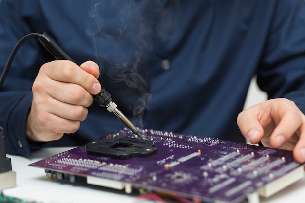 Close-up man repairing a computer motherboard