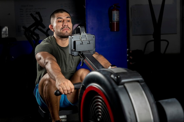 Close up of a man rowing on a machine in a crossfit gym