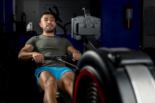 Close up of a man rowing on a machine in a crossfit gym