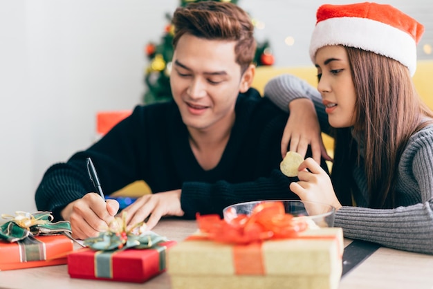 Close up man's hand is writing on a blank Christmas postcard with a pen.