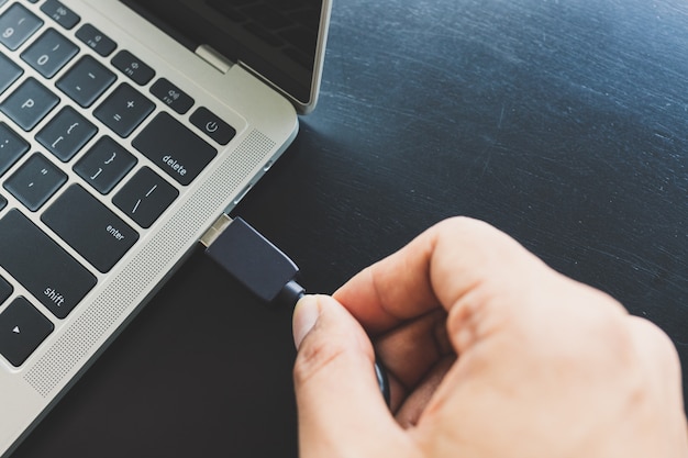 Close up of a man's right hand Going to connect the USB cable, take the external data into the laptop