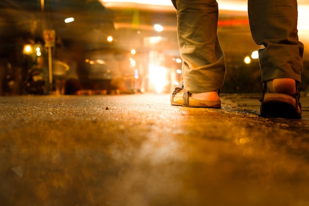 Close up of man sandals walking in city night.