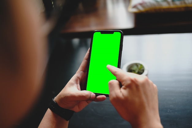 Close up of man using blank green screen cell phone order products for shopping online within the cafe.