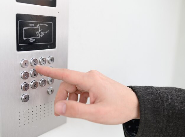 Close up of man using intercom at residential building entrance