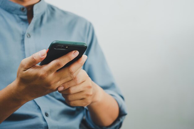 Close up of a man using mobile smart phone searching internet sending sms using text messenger or online bankingCopy space