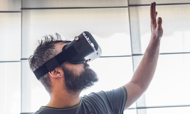 Photo close-up of man using virtual reality simulator against window