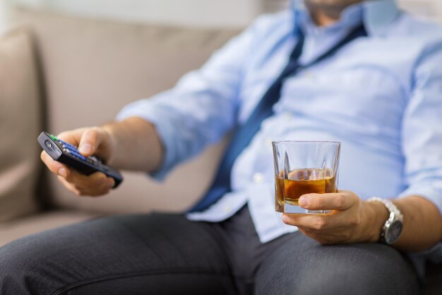 close up of man with tv remote drinking alcohol