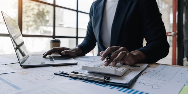 Close up man working about financial with calculator at his office to calculate expenses Accounting concept