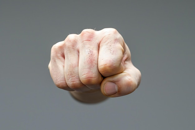 Close up of a mans fist from the front holding out a hand for help or support on a grey background