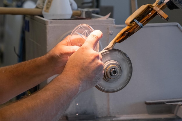 Close up mans hand making a glass carving on the new vase