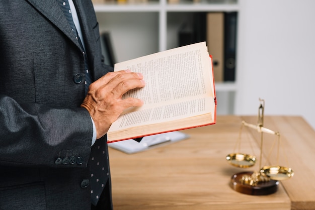 Close-up of mature lawyer reading law book in the courtroom