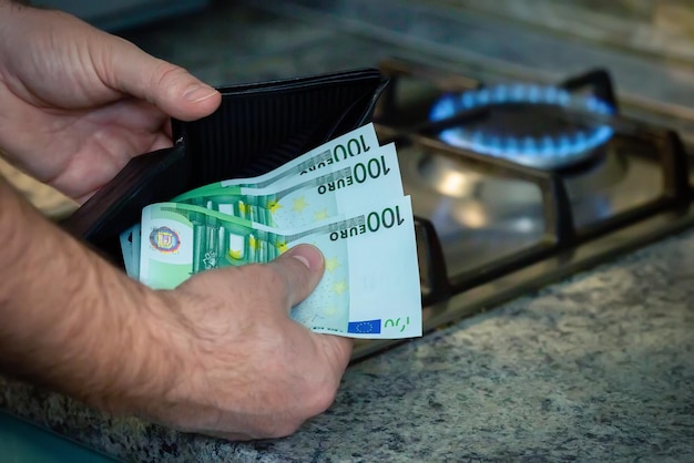 Close up of mens hands with a purse and euro banknotes on the background of a gas stove