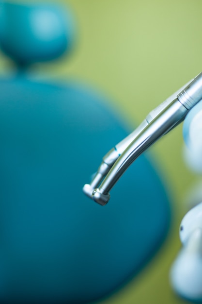 Close up of the metallic dentist tools with blue dentist chair