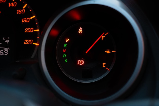 Close up of meter panel with the needle pointing at F on black blackground, fill the gas car tank