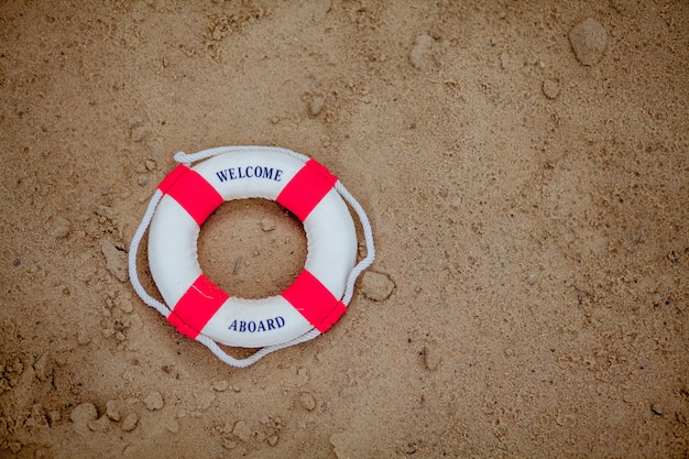 Close-up Of Miniature Lifebuoy Dig In The Sand At Beach