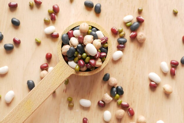 Close up of mixed beans in a wooden spoon on table