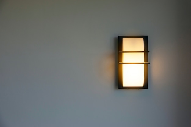 Close-up of a modern design of a wall mounted house lighting on white cement walls.