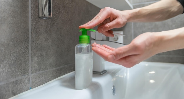 Close up modern guy pushing the dispenser with aniseptic gel