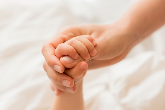 Close-up mom and baby holding hands