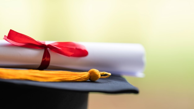 Photo close-up of a mortarboard and degree certificate put on table. education stock photo