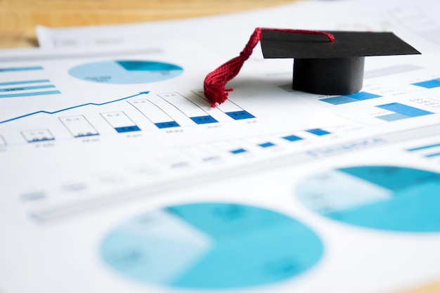 Close-up of mortarboard on graph charts