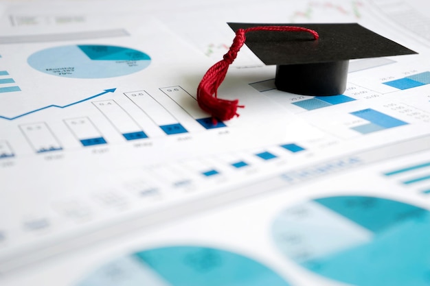 Photo close-up of mortarboard and graphs on table