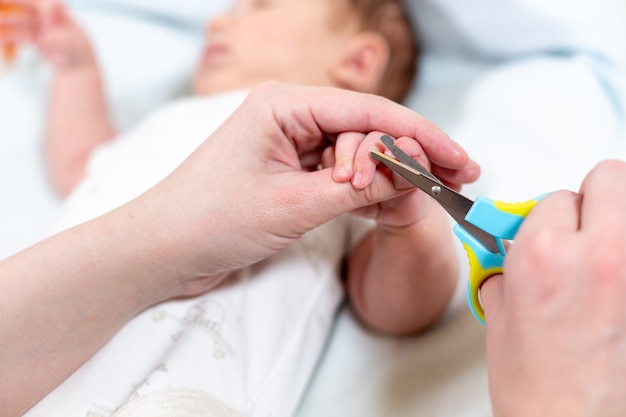 Close up of mother cutting babies nails with scissors. Nursing a child.