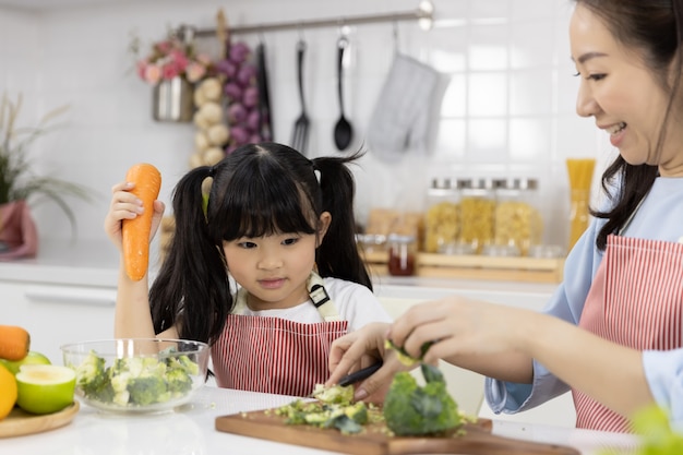 Close up of mother and daughter cutting vegetables