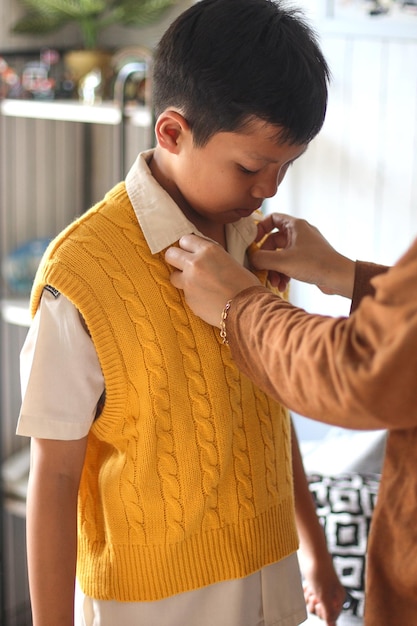 Close-up of mother hands tidied up her son uniform in the morning. Back to school preparation.