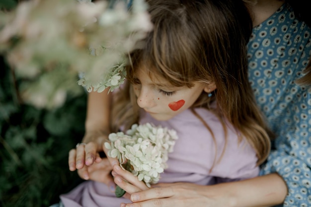 Close up mother is holding her young daughter outside in spring nature.