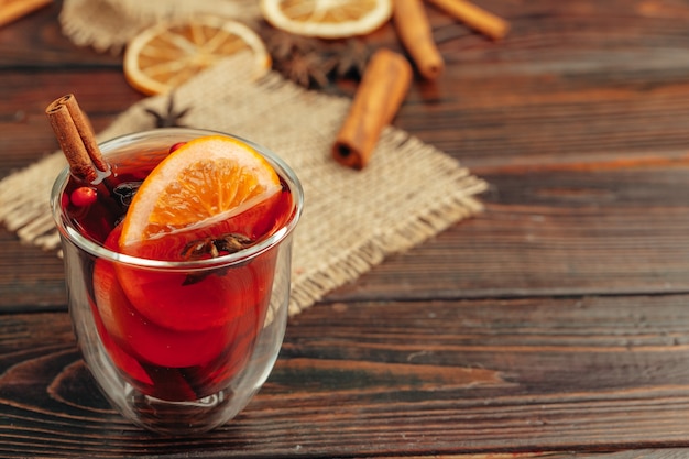 Close up of mulled wine cup with spices and berries on grey table