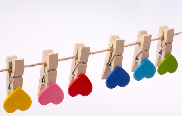 Close-up of multi colored clothespins hanging on rope against white background