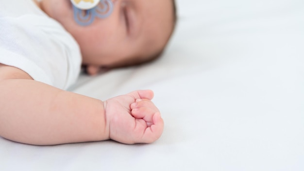 Close up of newborn boy hand on white sheet background Baby sleeping on the bed