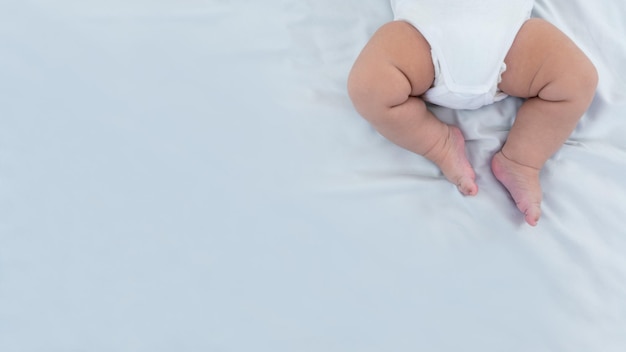 Close up of newborn boy legs on white sheet background Baby sleeping on the bed