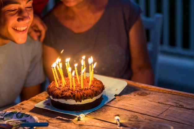 Close up of night party and birthday cake with candles Young teenager boy and grandfathers enjoy and celebrate together with happiness Age and aging generations concept event